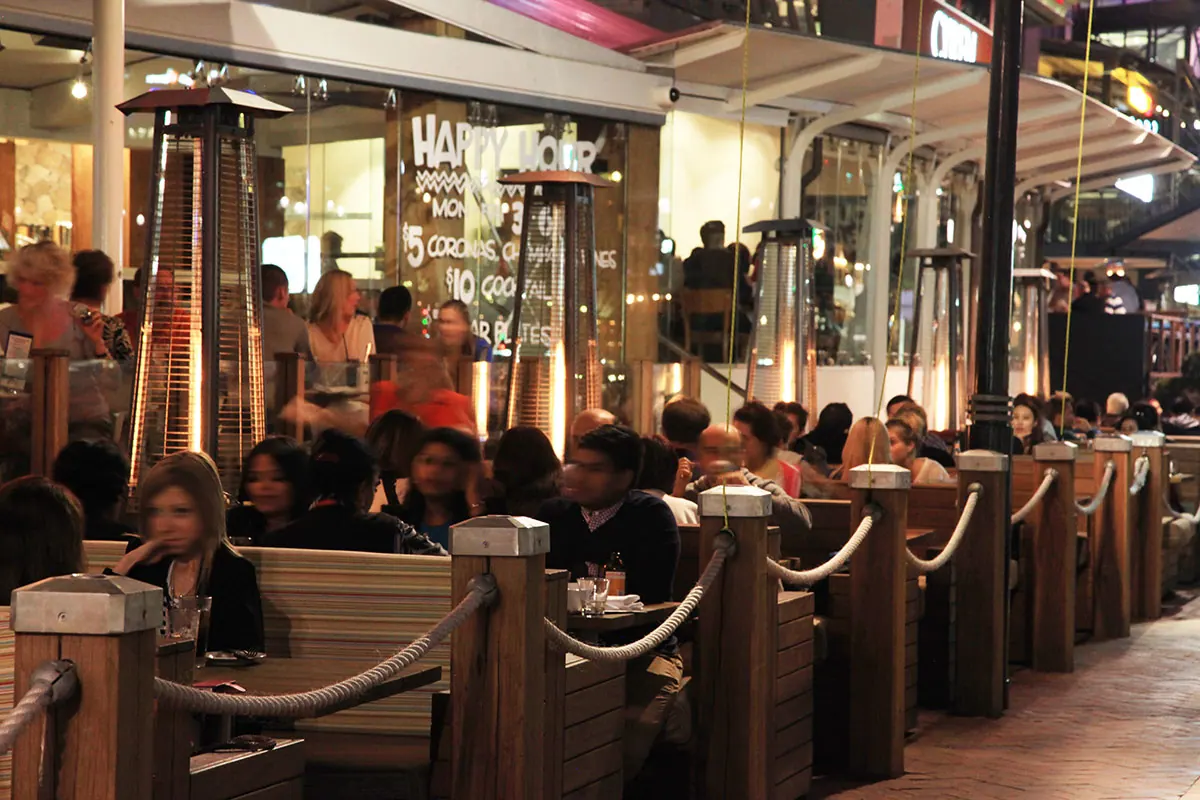Firestick heaters along a busy restaurant terrace at night